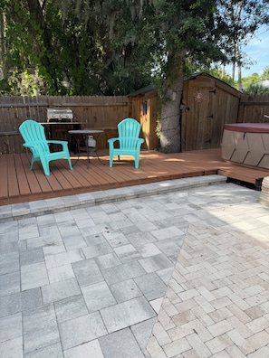 A patio with two Adirondack chairs, a grill, and a small shed.