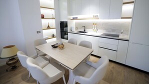 A modern kitchen with white cabinetry, a black sink, and a dining table with chairs.