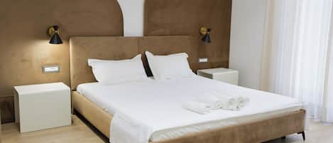 Habitación de hotel con una cama grande, dos mesitas de noche, una lámpara de pared y un enchufe.