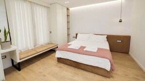 Une chambre moderne avec un lit, des tables de chevet, un banc et une plante en pot.