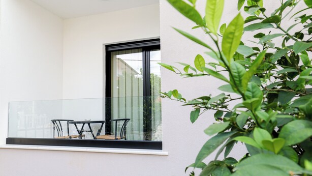 Un balcon doté d’une balustrade en verre, d’une table et de deux chaises.