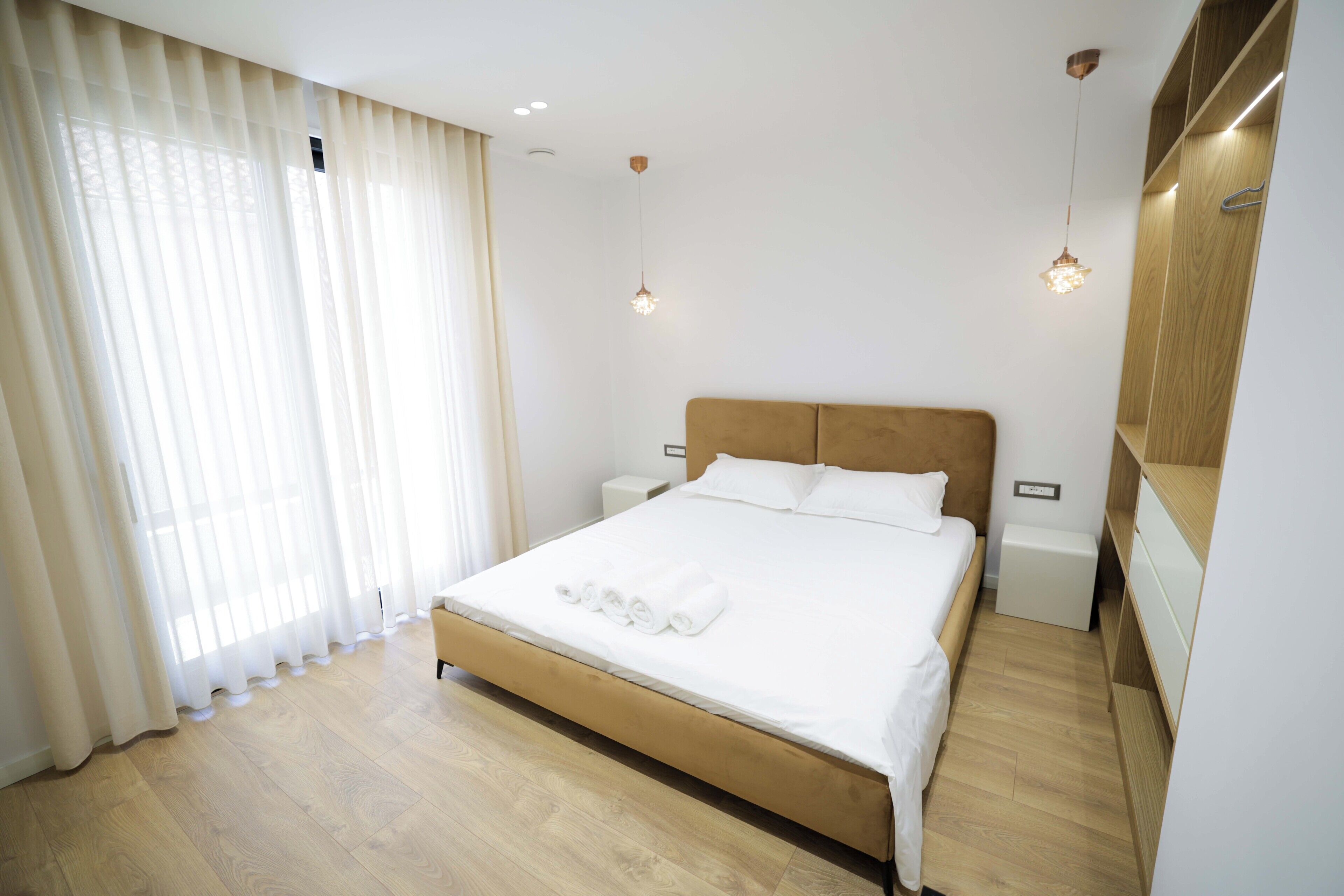 Ein Hotelzimmer mit einem großen Bett, einem Holzkopfende, weißer Bettwäsche und einem Holzboden.