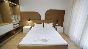 A hotel room with a large bed, two bedside tables, a wardrobe, and a window with curtains.