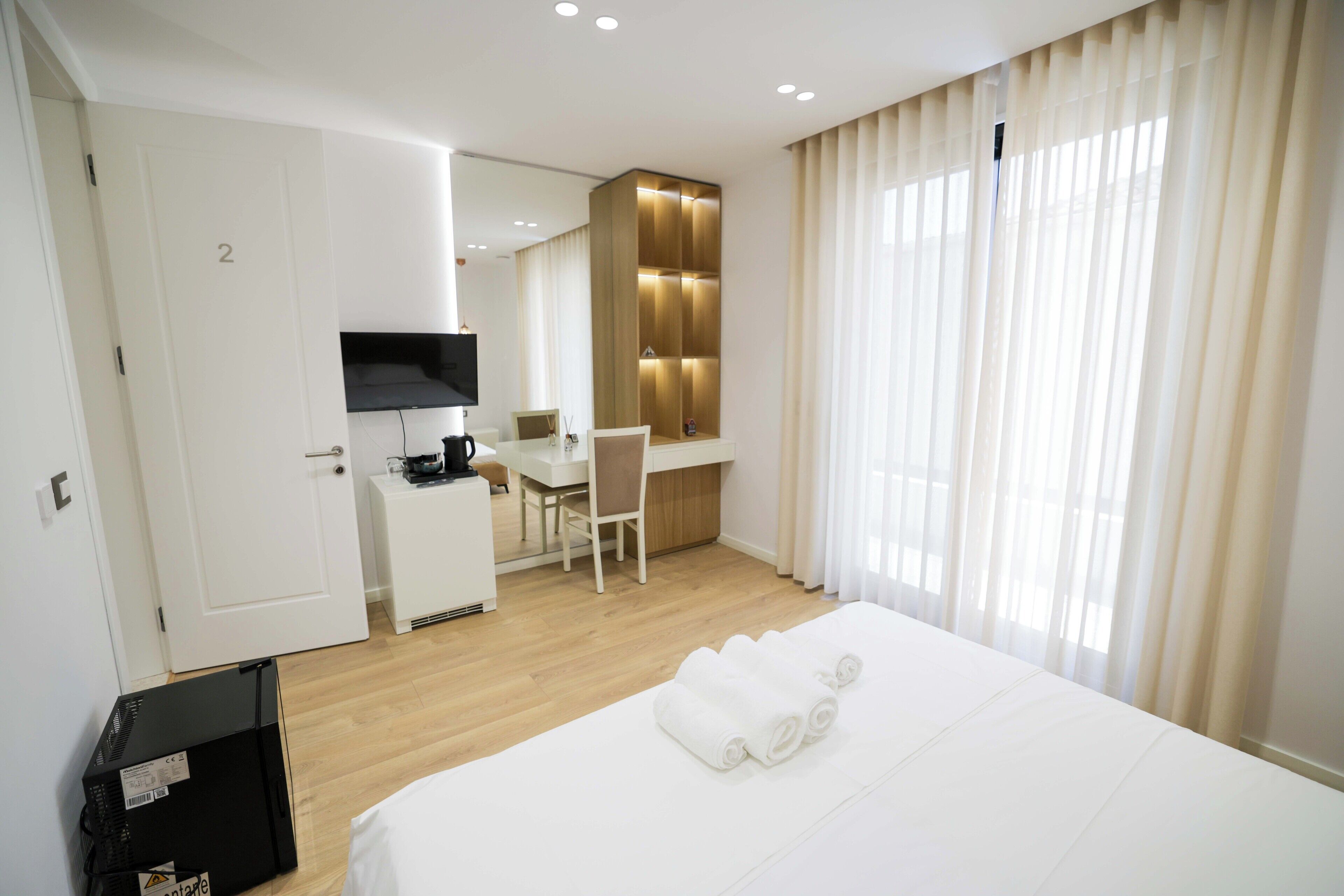 A hotel room with a bed, a desk, a chair, a television, and a window with curtains.