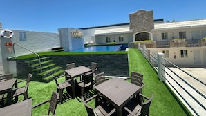 Zona de piscina con muro de piedra, un flotador salvavidas y mobiliario exterior.