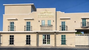 Un hotel con fachada color beige, balcones y un letrero que dice 'ROYAL MADEIRO INN'.