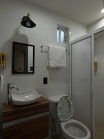 Un baño con lavamanos, inodoro y espejo.