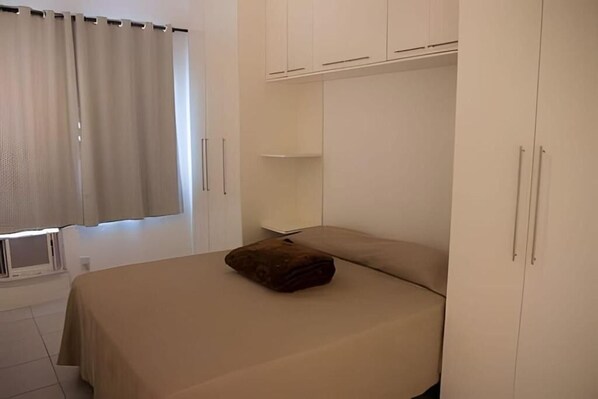 A bedroom with a bed, a window with curtains, and white wardrobes. - EXECUTIVE IN - IDEAL FOR FAMILIES (Rio de Janeiro)