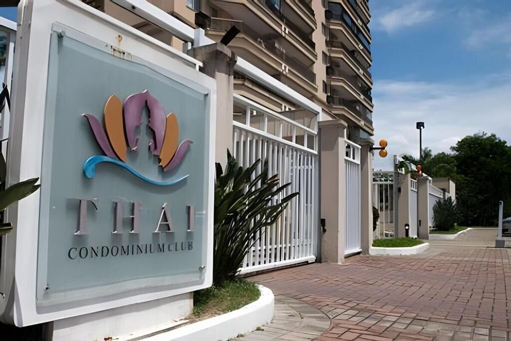 A sign for 'Thai Condominium Club' with a modern logo, a gated entrance, and a paved driveway.
