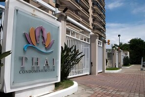Schild für den 'Thai Condominium Club' mit modernem Logo, geschlossenem Eingangsbereich und befestigter Auffahrt.