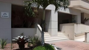 Ingresso di un edificio con una palma, delle scale e un cartello.