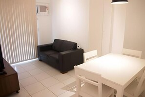 A room with a white table, a dark sofa, and a white lamp. - EXECUTIVE IN - IDEAL FOR FAMILIES (Rio de Janeiro)