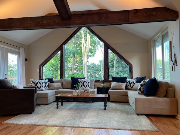 Un salón amplio con techo alto, ventanas grandes y una zona de estar acogedora.