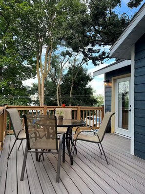 Una terraza con mesa y sillas de vidrio, rodeada de árboles.