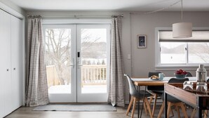 Et moderne køkken med spiseplads, store vinduer og udsigt til en sneklædt terrasse.