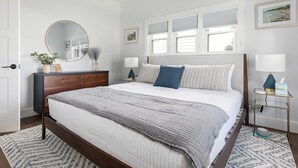 Ein Schlafzimmer mit Bett, Nachttischen, einem Schminktisch und Spiegel sowie gerahmten Bildern an der Wand.