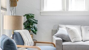 Ein Wohnzimmer mit einer Couch, zwei Sesseln, einer Lampe und einer Pflanze.