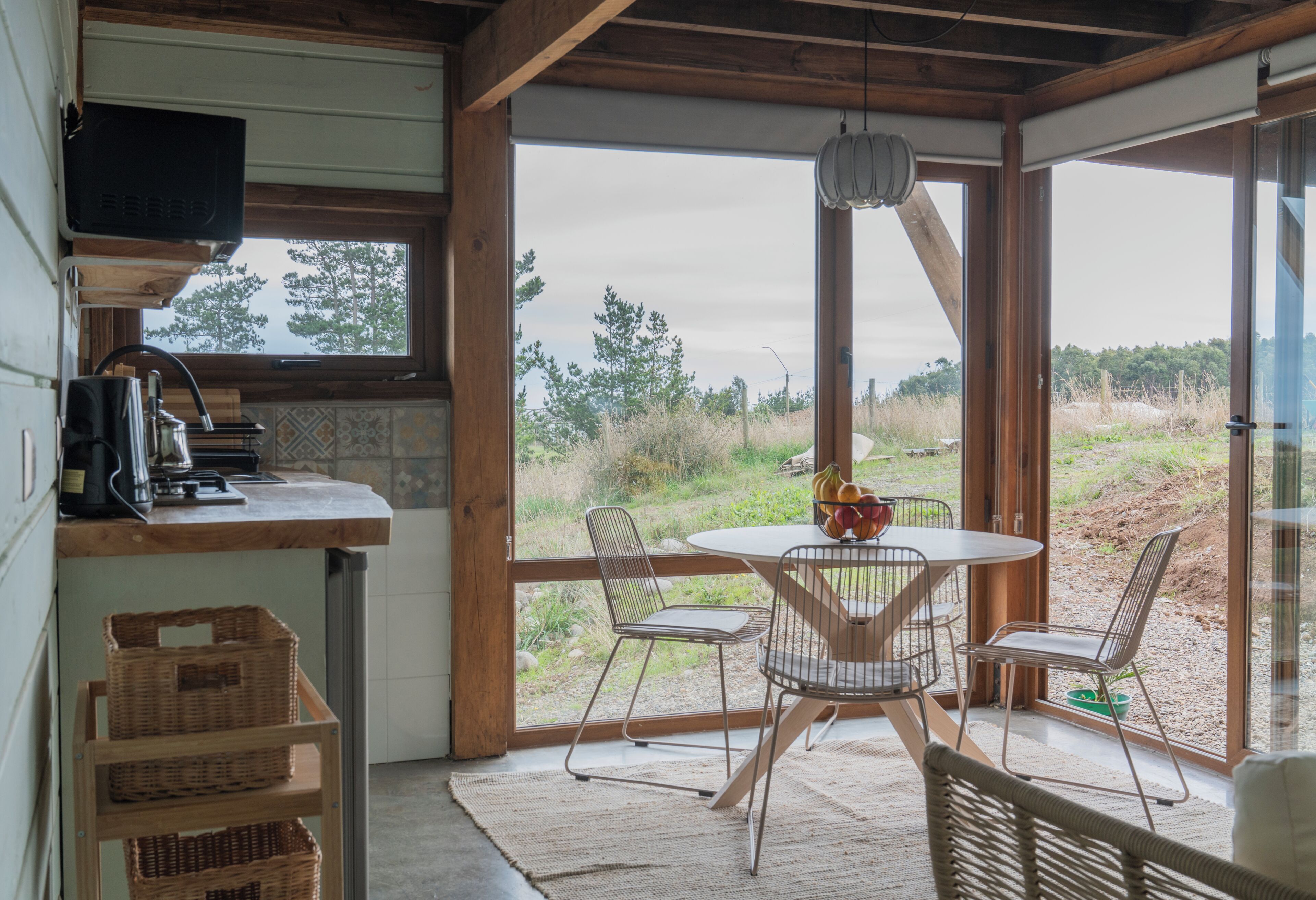 Una cocina con ventana, una mesa de comedor con sillas y vistas al exterior.