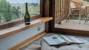 A window seat with a bottle of wine, a glass, and an open magazine. - La Vertiente Pullay (Cobquecura)