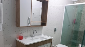 A bathroom with a white sink, a mirror, and a glass shower enclosure.