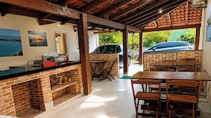 A kitchen with a brick backsplash, wooden counter, and a dining area with a table and chairs.