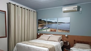 A bedroom with a bed, a nightstand, a wall-mounted air conditioner, and a window with curtains.