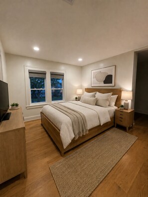 Ein Schlafzimmer mit einem Bett, Nachttischen, einem Fernseher und einem Fenster.