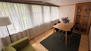 A room with a wooden ceiling, a dining table with chairs, a green sofa, a lamp, and a cabinet with glass doors. - Historic Summer cottage in Jurmala (Jūrmala)