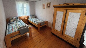 A room with two wooden beds, a wardrobe, and a ceiling light fixture. - Historic Summer cottage in Jurmala (Jūrmala)