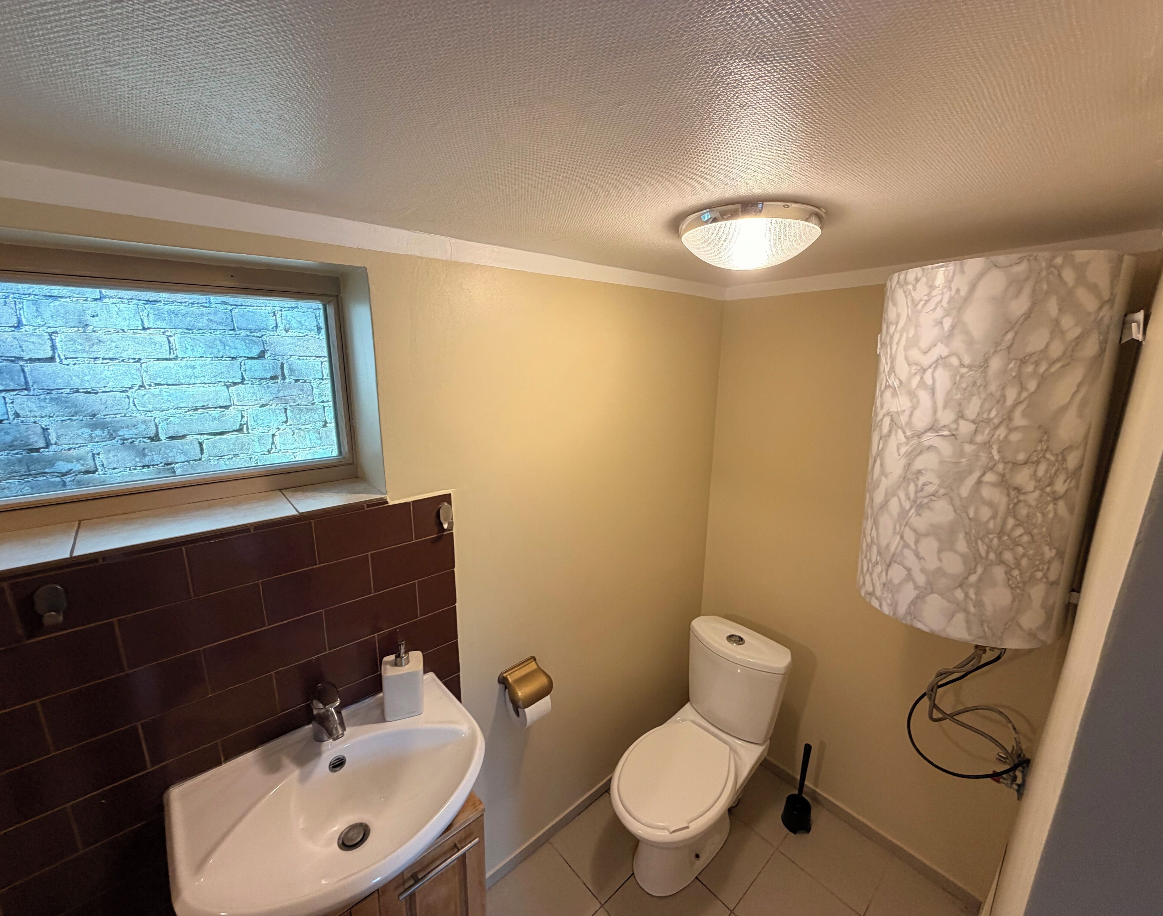 A bathroom with a window, a sink, a toilet, and a shower curtain.