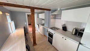 A modern kitchen with white cabinets, a wooden beam ceiling, a gas stove, and a dishwasher. - Historic Summer cottage in Jurmala (Jūrmala)