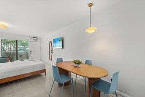A modern bedroom with a bed, a dining table with chairs, a potted plant, and a beach-themed picture on the wall. - Charming studio apartment in delightful Miami Beach with cool AC (Miami Beach)