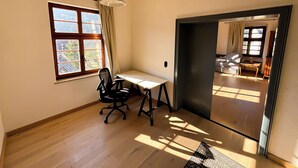Una habitación con escritorio, silla y un amplio ventanal con cortinas.