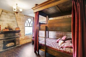 Ein Zimmer mit einem Himmelbett, einem Kamin und einer Steinsäule.