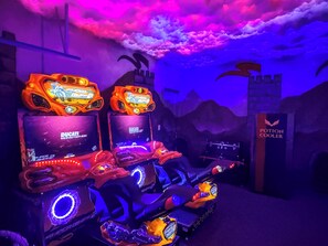 Rhythm-Spiele mit LED-Beleuchtung und markierten Bildschirmen vor einer Kulisse mit Burg und Himmelgemälde.