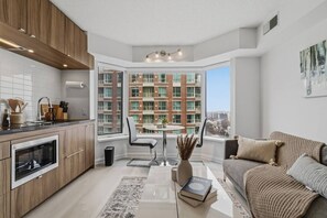 A modern apartment with a kitchen, dining area, and living room, featuring large windows and a city view.