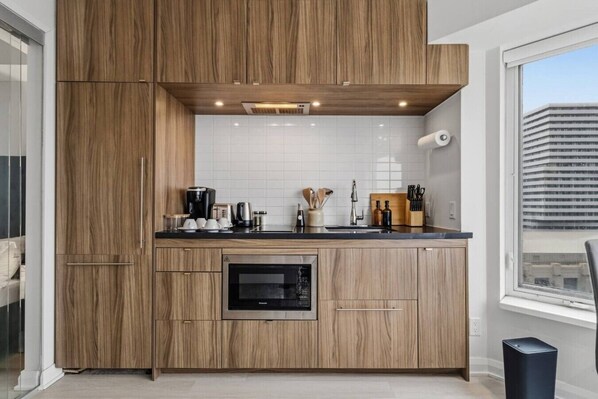 A modern kitchen with wooden cabinets, a built-in oven, and a window with a city view.