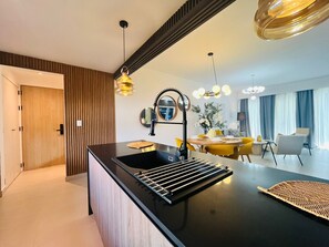 A modern kitchen with a black countertop, a sink, and a dining area with yellow chairs. - 2-bedroom apartment in fantastic Punta Cana with AC and gym (Punta Cana)