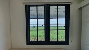 A room with a large window, a wooden bench, and a view of a green field. - Aob-oun Homestay By Zuzu (Pak Chong)
