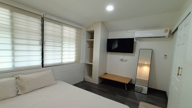 A bedroom with a bed, a TV, a mirror, and a wardrobe. - Aob-oun Homestay By Zuzu (Pak Chong)