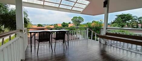 A covered outdoor area with a wooden floor, a table, and two chairs.
