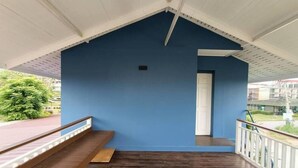 A balcony with a blue wall, wooden floor, and white railing. - Aob-oun Homestay By Zuzu (Pak Chong)
