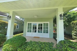 Ein Haus mit überdachter Veranda, einer weißen Tür und einer Fußmatte.