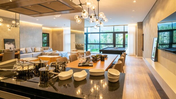 Una cucina moderna con isola centrale, zona pranzo e tavolo da biliardo.
