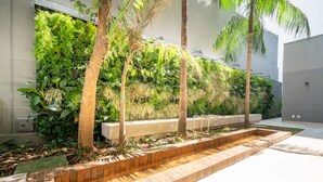 Uno spazio esterno moderno con un giardino verticale, un fioriera in mattoni e una panchina in cemento.