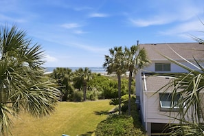 A residential property with a view of the ocean, a well-maintained lawn, and palm trees. - Modern Oceanfront Beach Club Villa *Unit 64* in Wild Dunes w/Community Pool! Ocean Views & Breezes! (Isle Of Palms)