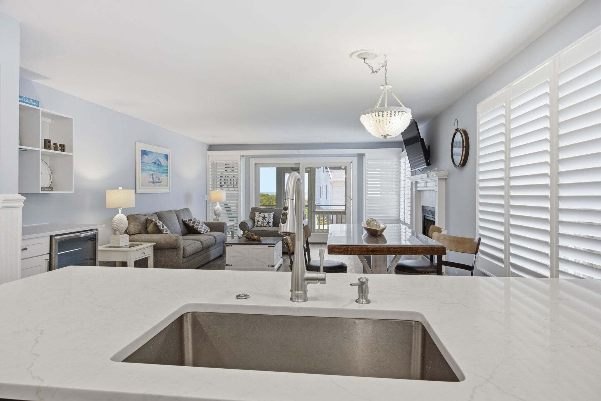 A modern kitchen with a large island, a dining area with a table and chairs, a sofa, and a fireplace.