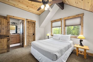 Ein Schlafzimmer mit einem großen Bett, Holzboden und einem Fenster mit Jalousien.