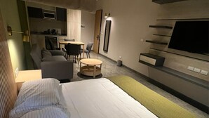 A hotel room with a bed, a sofa, a small round table, a TV, and a kitchenette. - Acogedor MiniLoft 202 (Ciudad de México)
