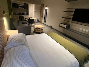 A hotel room with a bed, a sofa, a small round table, a TV, and a kitchenette. - Acogedor MiniLoft 202 (Ciudad de México)